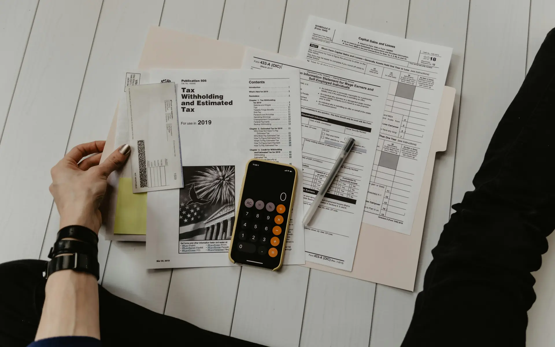 Manos revisando facturas en papel junto a una calculadora